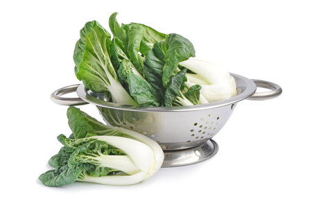 Colander with fresh pak choi cabbage on white backgroundの写真素材