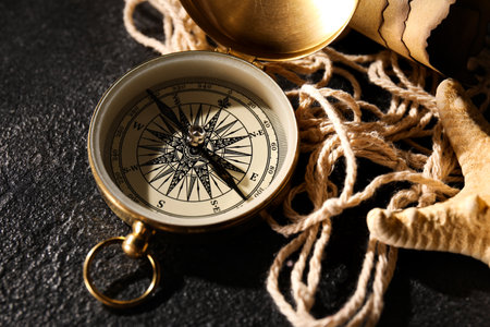 Golden compass, rope and starfish on dark background, closeupの写真素材