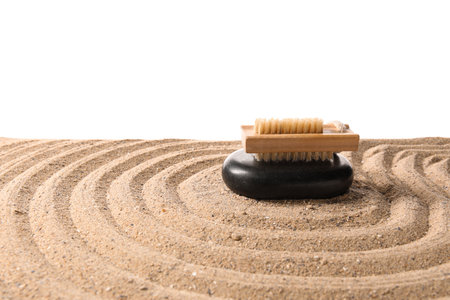 Massage brush with spa stone on sand against white backgroundの写真素材