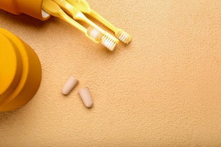 Foam earplugs and toothbrushes on color background