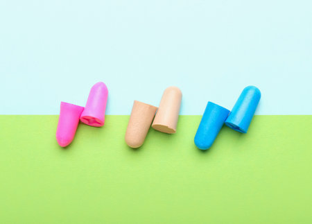 Different ear plugs on color background