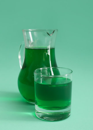 Jug and glass of matcha tea on green backgroundの写真素材
