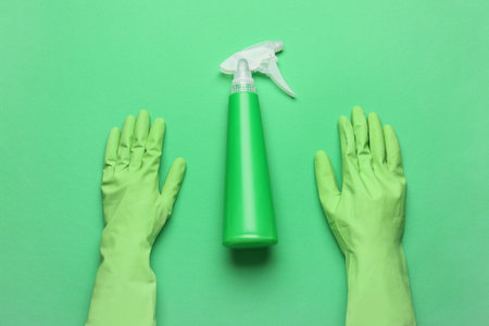Rubber gloves and bottle of detergent on green backgroundの写真素材