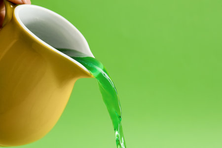 Woman pouring matcha tea on green background, closeupの写真素材