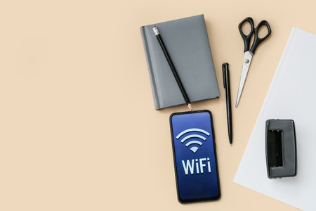 Stationery supplies and mobile phone with WiFi symbol on color background