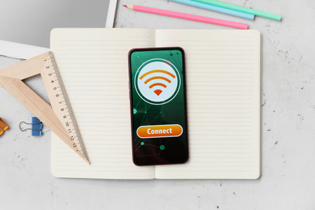 Different stationery supplies and mobile phone with WiFi symbol on light background