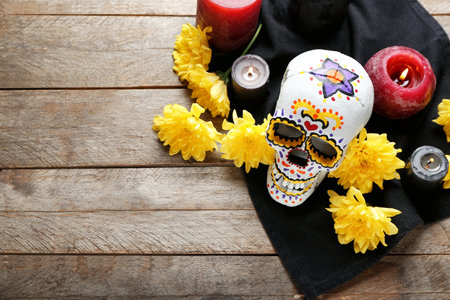 Painted human skull for Mexico's Day of the Dead (El Dia de Muertos), flowers and candles on wooden backgroundの写真素材