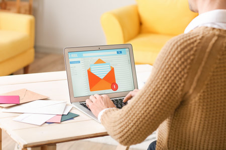 Young man with laptop checking his e-mail at homeの写真素材