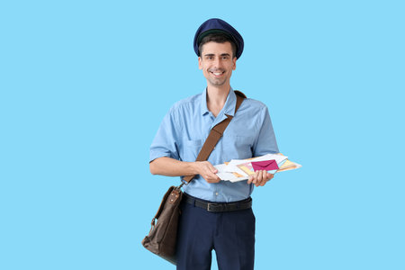 Handsome young postman with letters on color background