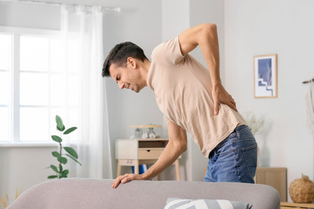 Young man suffering from back pain at home