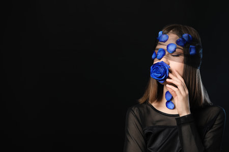Beautiful young woman with blue rose on dark backgroundの写真素材