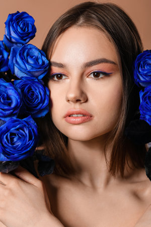 Beautiful young woman with blue roses on color backgroundの写真素材