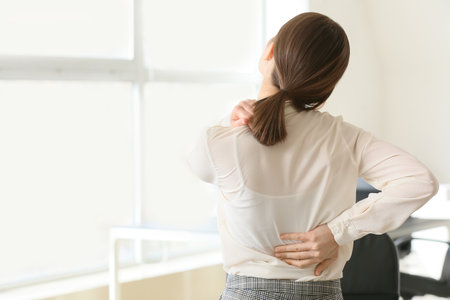 Young businesswoman suffering from back pain in officeの写真素材