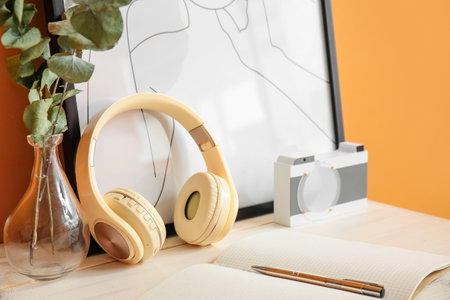 Modern headphones with vase and picture near color wall