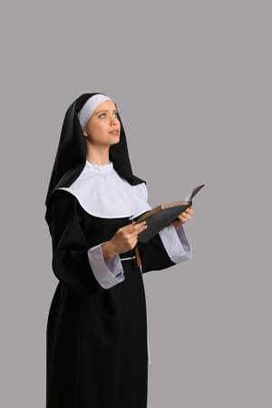 Young nun with Bible on gray backgroundの写真素材
