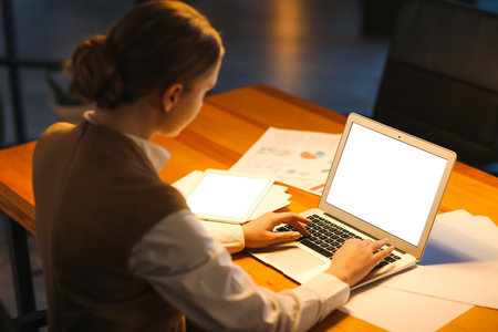 Young woman working on laptop in office at nightの写真素材