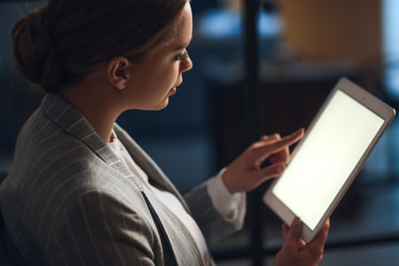 Young woman with tablet computer in office at nightの写真素材