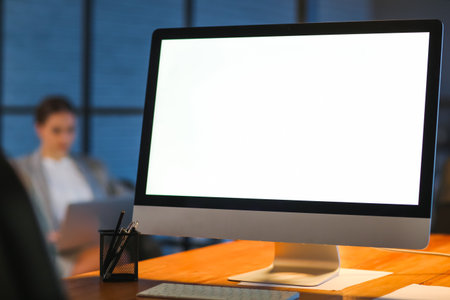 Modern computer on table of young woman in office at night