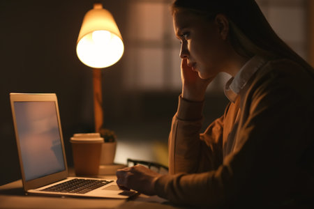 Young woman working on laptop in the eveningの写真素材