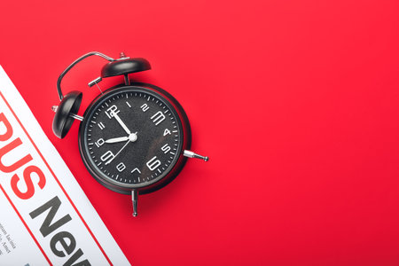 Stylish alarm clock and newspaper on color backgroundの写真素材