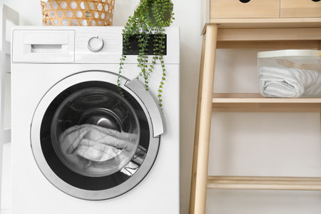 Modern washing machine with laundry in bathroomの写真素材