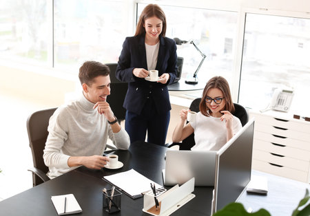 Business colleagues drinking coffee while working in officeの写真素材