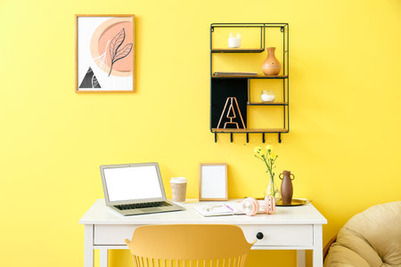 Modern workplace with laptop near color wallの写真素材