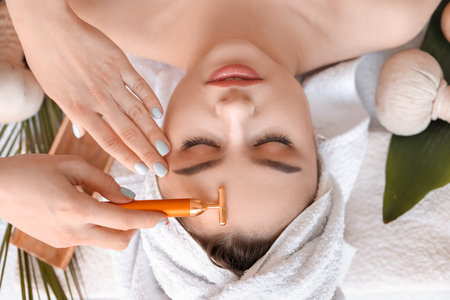 Young woman receiving face massage in beauty salon