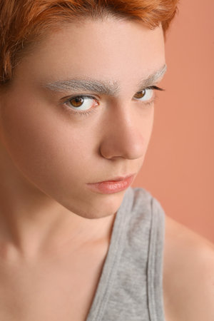 Teenage boy with dyed eyebrows on color background, closeupの写真素材