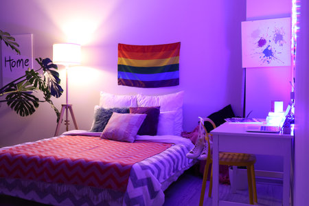 Flag of LGBT hanging on wall in interior of bedroom at nightの写真素材