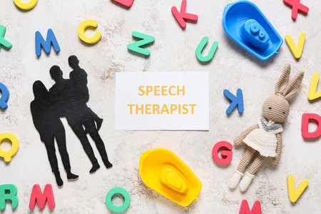 Paper with text SPEECH THERAPIST, toys and family figure on grunge backgroundの写真素材