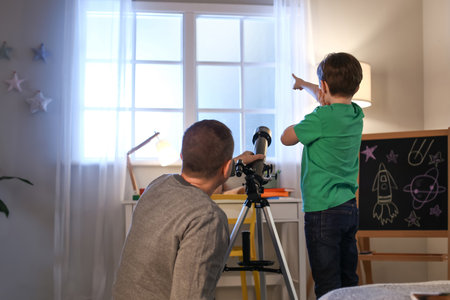 Little boy and his father looking at the stars through telescope in the eveningの写真素材