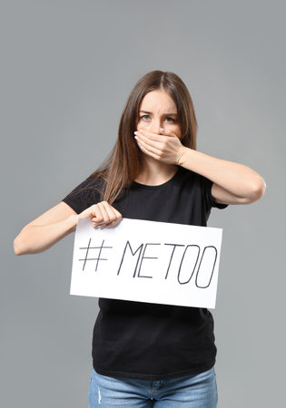 Young woman holding paper with hashtag MeToo on gray backgroundの写真素材