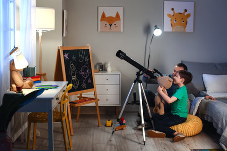 Little boy and his father looking at the stars through telescope in the evening