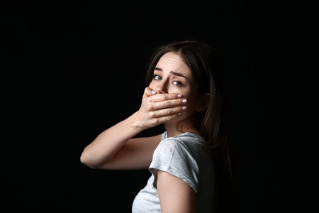 Scared young woman on dark background. concept of harassmentの写真素材
