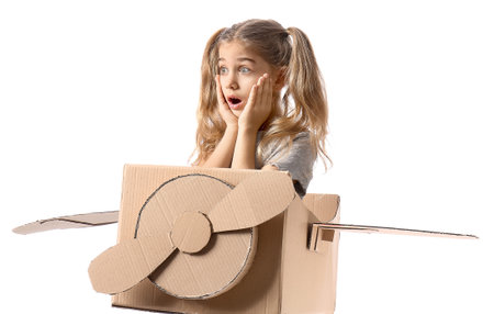 Shocked little girl with cardboard airplane on white backgroundの写真素材