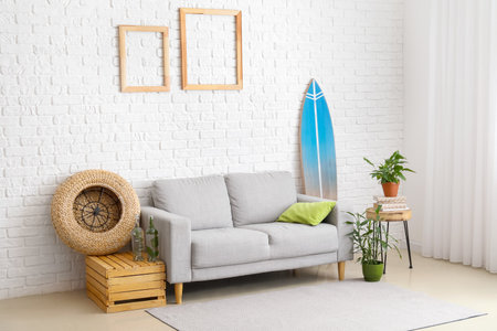 Interior of modern stylish room with surfboard, sofa and houseplantsの写真素材