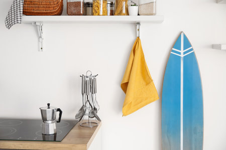 Interior of modern kitchen with surfboard near white wallの写真素材