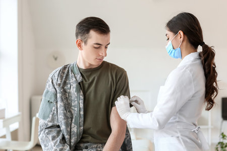 Doctor vaccinating patient against covid-19 in clinicの写真素材