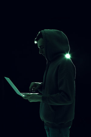 Silhouette of hacker with laptop on dark backgroundの写真素材