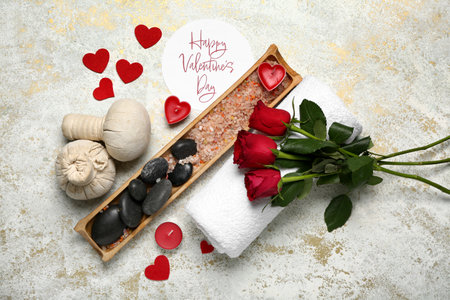 Beautiful spa composition for Valentine's Day with flowers, herbal bags, sea salt, stones and candles on light backgroundの写真素材