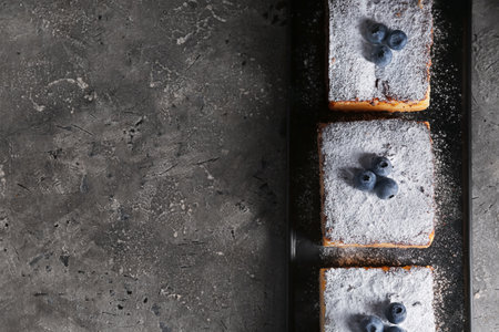 Pieces of cheese pie with blueberries on dark grunge table