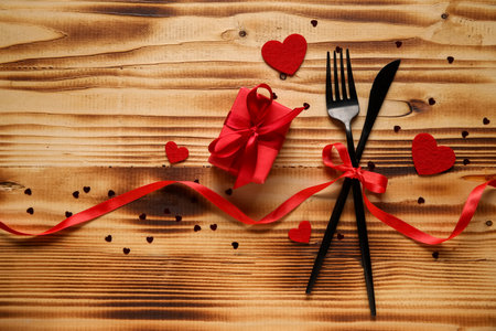 Cutlery for Valentine's Day with bow, hearts and gift on wooden backgroundの写真素材