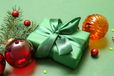 Gift with Christmas balls and fir branches on green background, closeupの写真素材