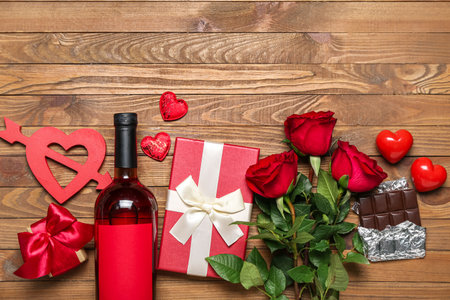 Bottle of wine, roses, gifts and chocolate on wooden background. Valentine's Day celebrationの写真素材