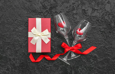 Glasses with hearts and gift on dark background. Valentine's Day celebrationの写真素材