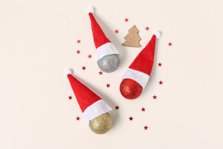 Composition with Santa hats, Christmas balls and sequins on light background