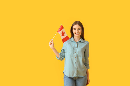Beautiful young woman with the flag of Canada on color backgroundの写真素材