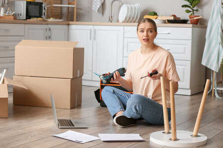 Troubled young woman assembling furniture at homeの写真素材