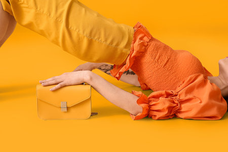 Lying young woman with bag on yellow backgroundの写真素材